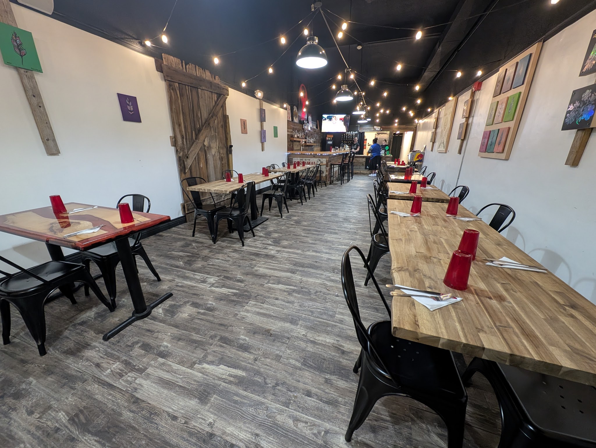 Ignition Eatery interior with butcher-block tables, black metal chairs, barn door accents and string lights