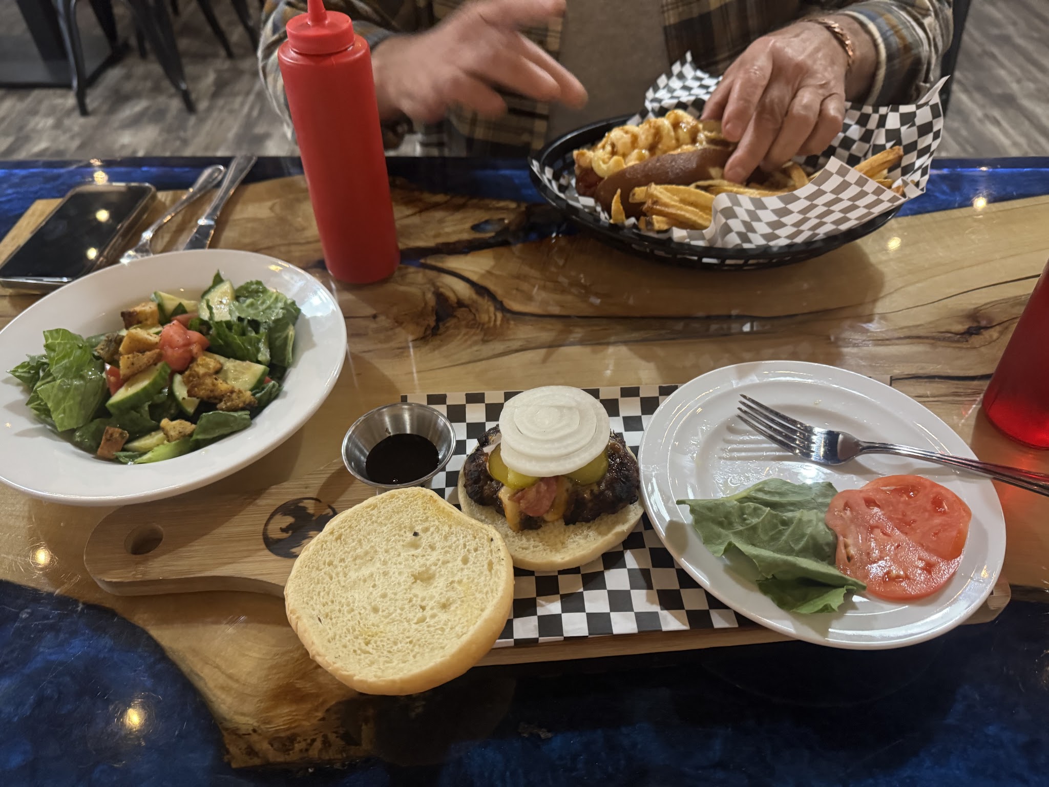 Burger with salad and fries on butcher-block table