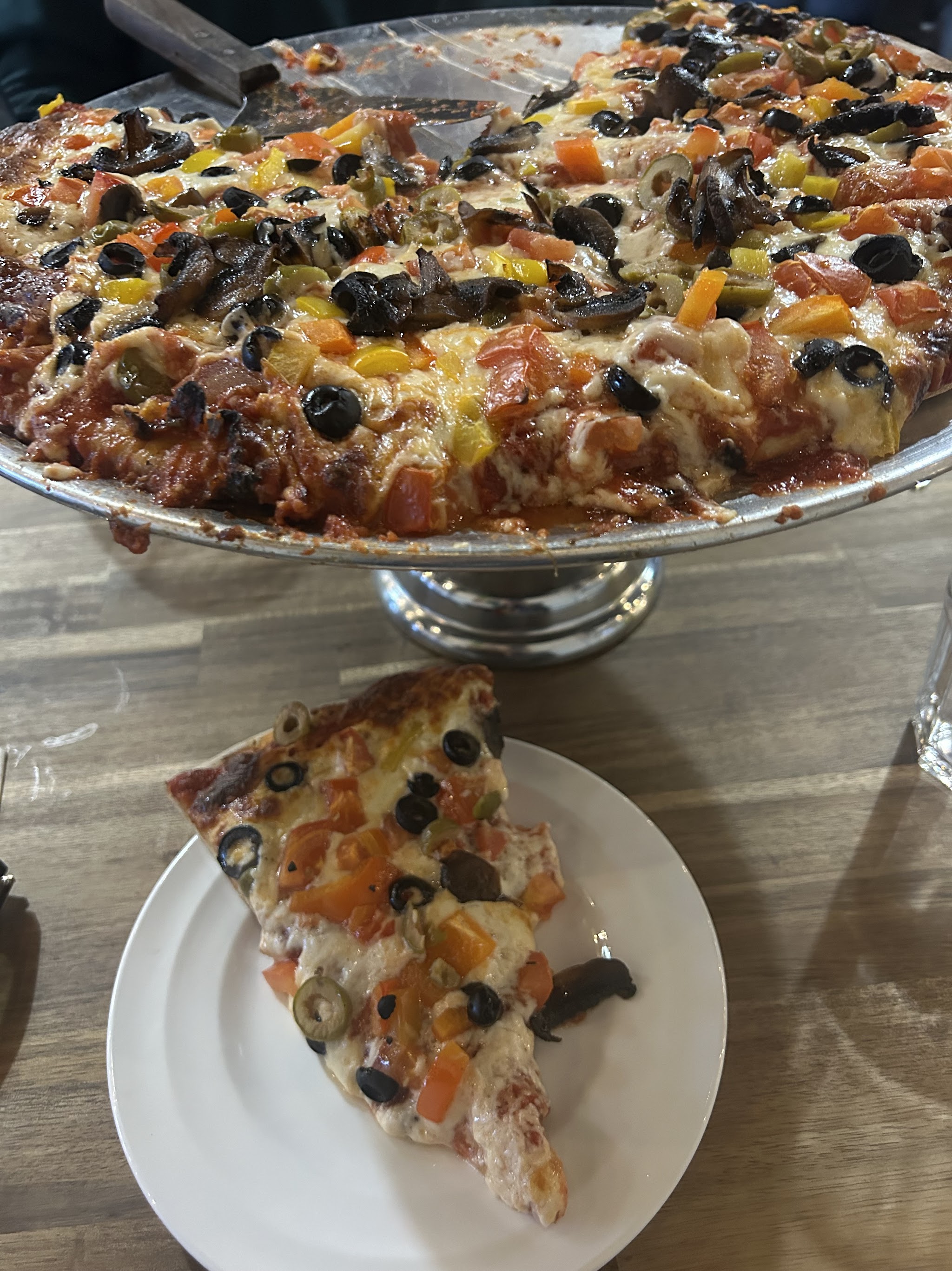 Veggie pizza with olives and peppers on a stand