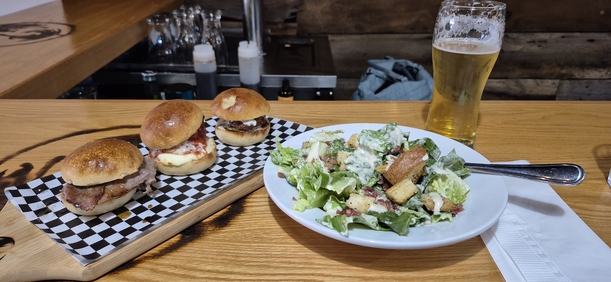 Sliders with caesar salad and a pint of beer at the bar